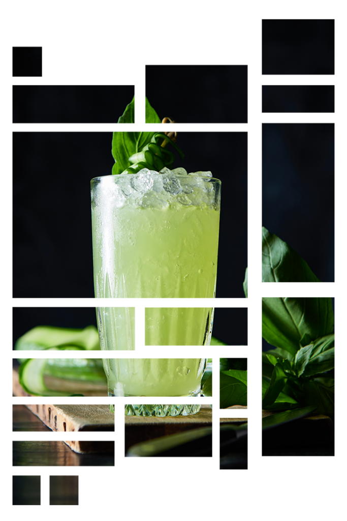 Grøn cocktail med agurk og mynte som pynt. Står på et stykke træ