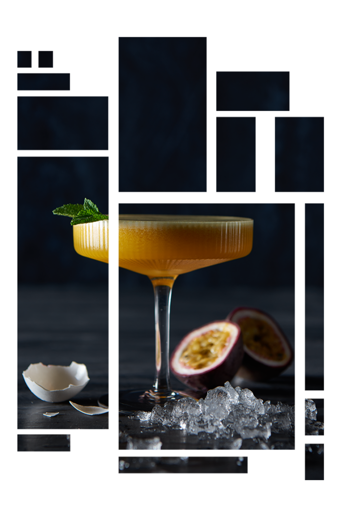 Gul cocktail i højt glas, ved siden af lægger en æggeskal og en passionsfrugt