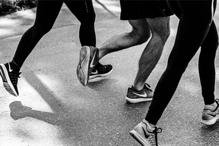 Tre personer med Nike sko der er ude og løbe. Billedet er i sort hvid
